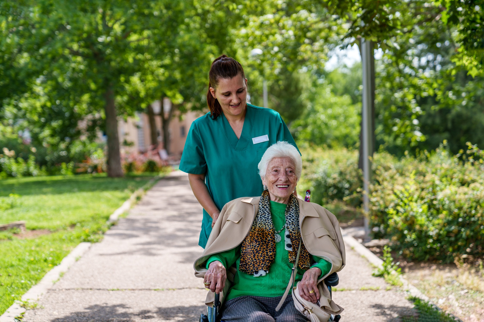 Senior Woman in Wheelchair Enjoying Sunny Day with Caregiver at Nursing Home